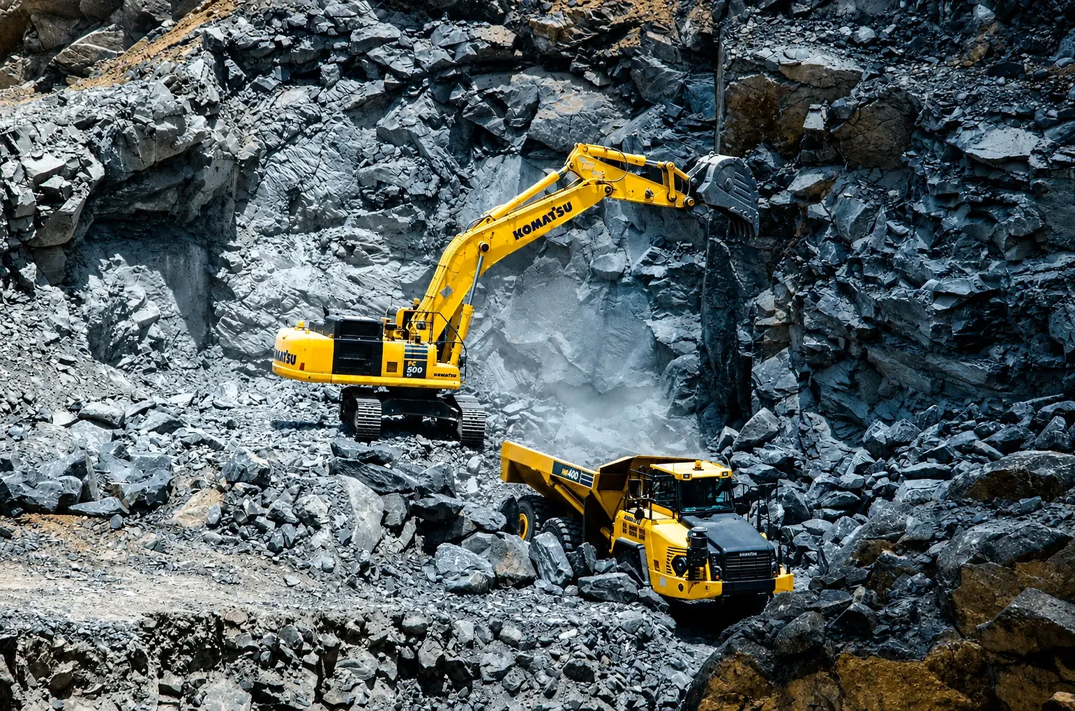 Excavator loading crushed rock at quarry face